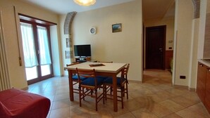 Un coin repas comprenant une table, des chaises, un téléviseur et une horloge murale.