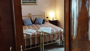 Un lit avec un cadre en métal, une table de chevet avec une lampe et un tableau accroché au mur.