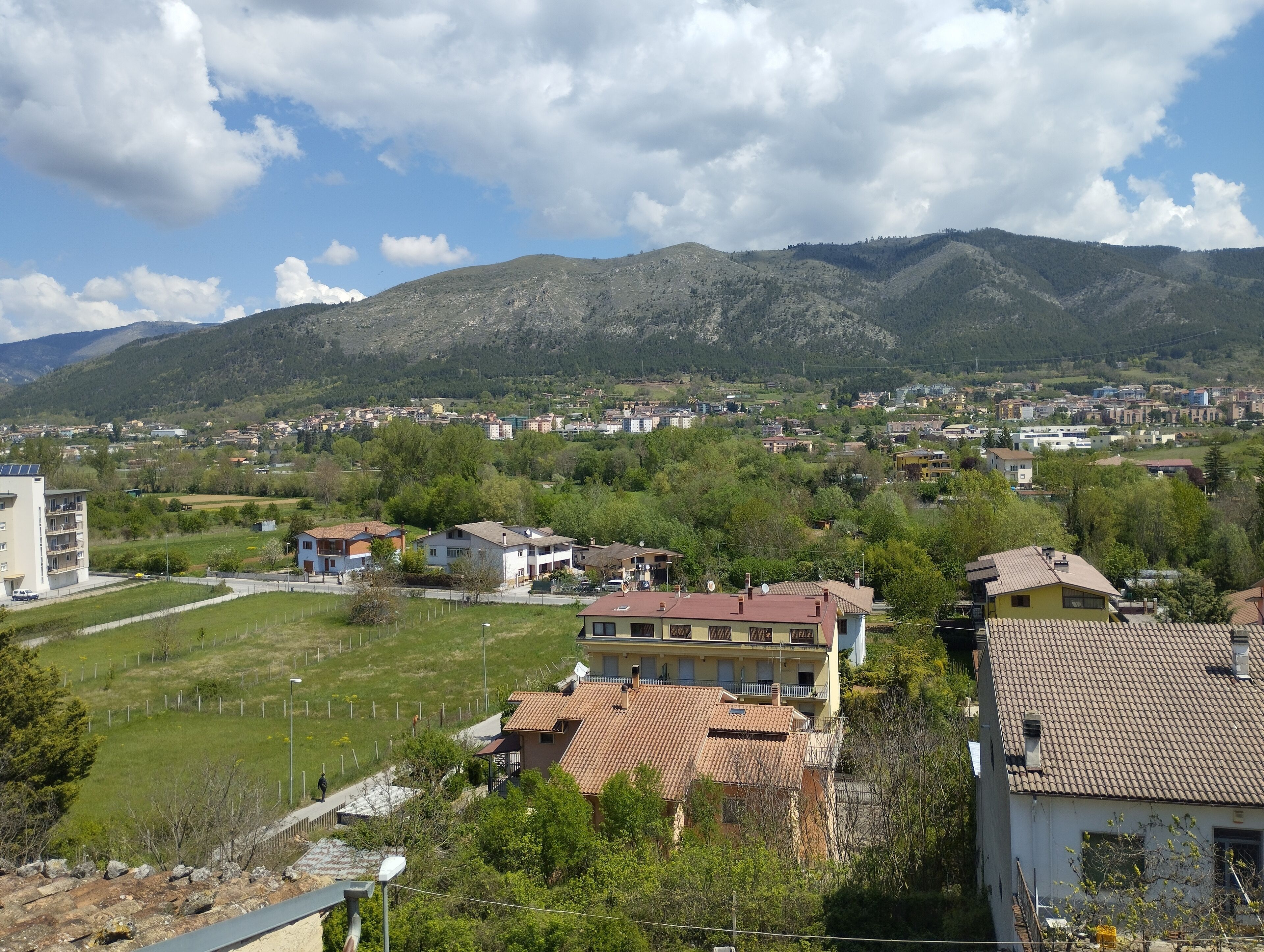 Un barrio residencial con casas, un parque pequeño y montañas al fondo.
