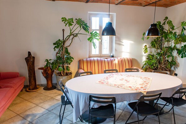 A dining area with a round table, chairs, and potted plants.