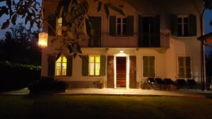 Une maison à deux étages avec un balcon, une porte d’entrée dotée d’une lumière et un petit jardin.