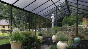 Une serre avec des plantes en pot et un mur de pierre en arrière-plan.
