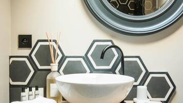 A bathroom with a round mirror, a white vessel sink, and a wooden vanity.