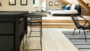 Une chambre mansardée avec un plafond en bois, un lit, un bureau et une chaise.