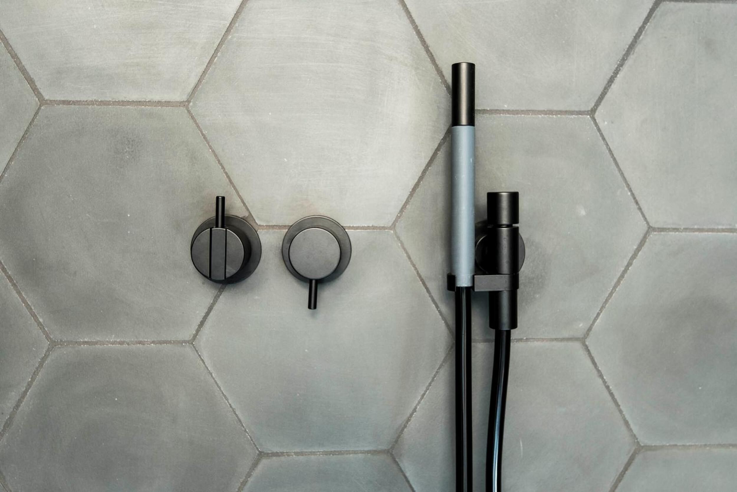 A bathroom with a hexagonal tile floor, a black faucet, and a silver handle.