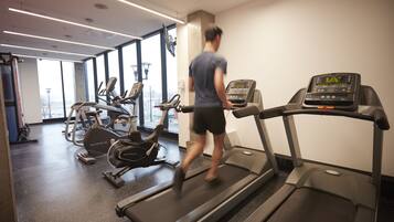 Un gimnasio con cintas de correr, bicicletas estáticas y elípticas.