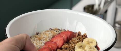 A bowl of food with strawberries, granola, and banana slices.