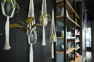 Una habitación con macramé para plantas y estantes con diversos objetos.