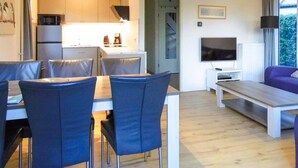 En moderne stue med spiseplads, fjernsyn og sofa.