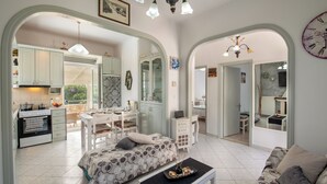 A spacious living area with a sofa, a coffee table, and a dining table. - Loggos Seaview Cottage with Pool by Konnect (Paxos)