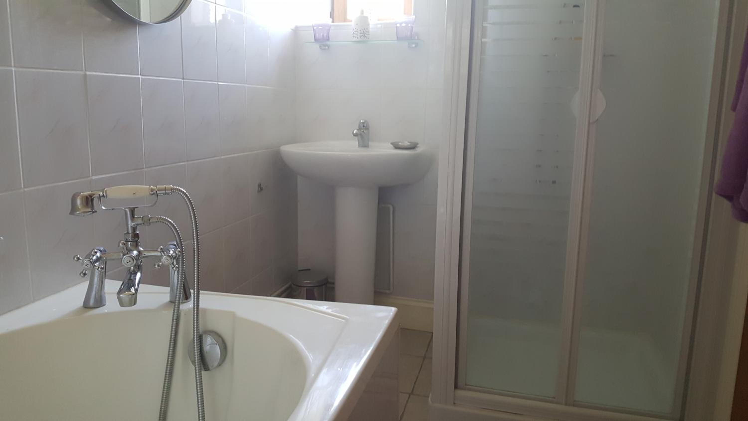Une salle de bain équipée d’une baignoire, d’un lavabo et d’une douche à parois en verre.
