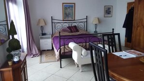 Un dormitorio con cama, mesitas de noche, escritorio y silla.