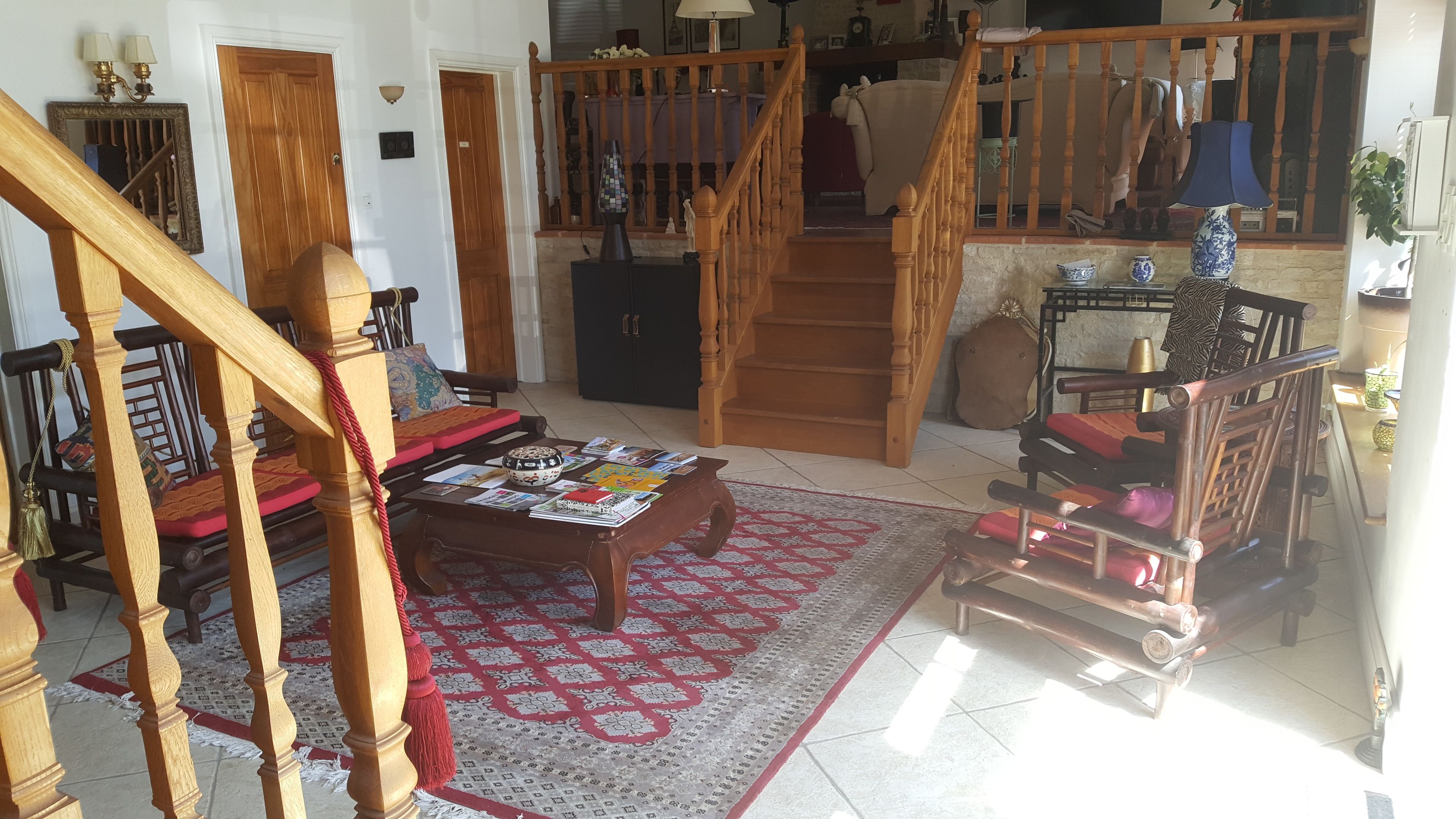 Ein Wohnzimmer mit einer Holztreppe, einem Couchtisch mit Zeitschriften und einem gemusterten Teppich.
