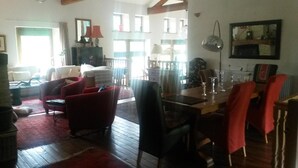 Amplia sala de estar con piso de madera, una mesa de comedor con sillas y un sofá rojo.