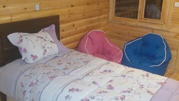 A wooden cabin bedroom with a bed, a window, and an air conditioning unit.