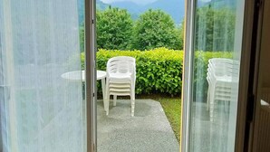 A sliding glass door leading to an outdoor seating area with a view of green hills and trees.