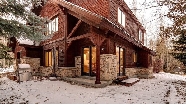 Enter a cozy cabin with a glass door leading into a warmly lit interior.