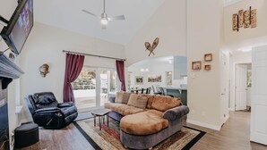 A spacious living room with a leather recliner, a large sectional sofa, and a fireplace. There is a dining area visible through a glass door. - 62sl - Hot Tub - Wifi - Fireplace - Pets Ok 3 Bedroom Home by RedAwning (Deming)