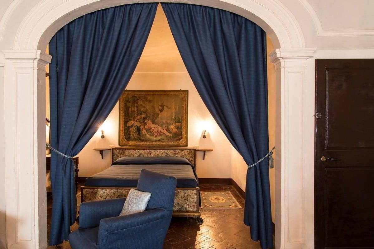 A bedroom with a bed, a chair, and a painting on the wall.