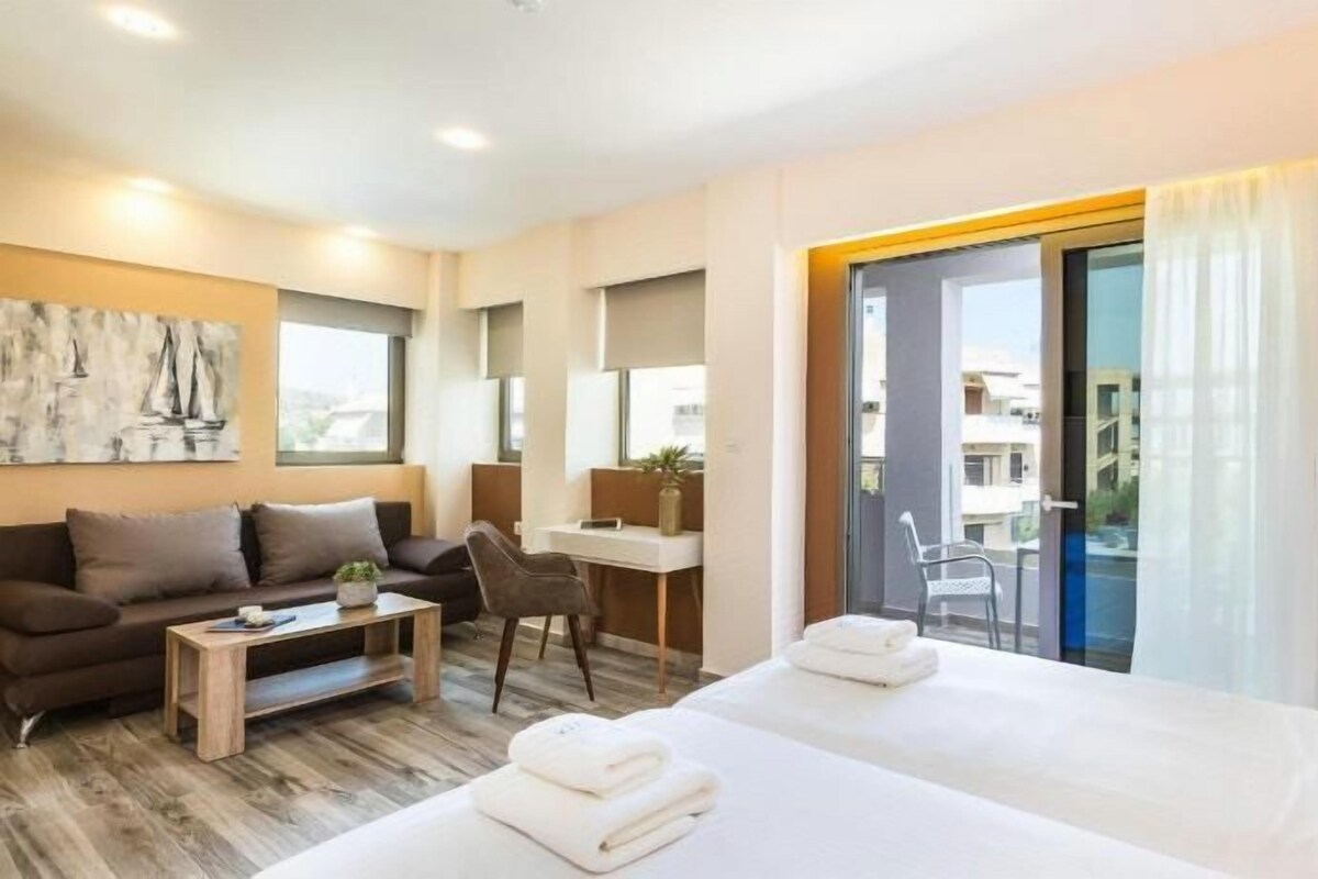 A hotel room with a bed, a desk, a chair, and a sofa.