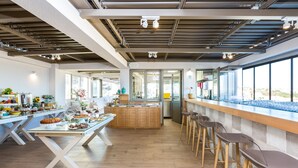 Una cocina moderna con una isla central, zona de bar con taburetes y grandes ventanales con vistas.
