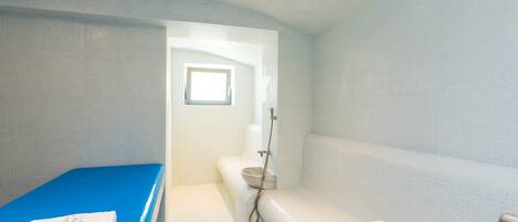 Un baño moderno con una bañera azul, zona de ducha y retrete.