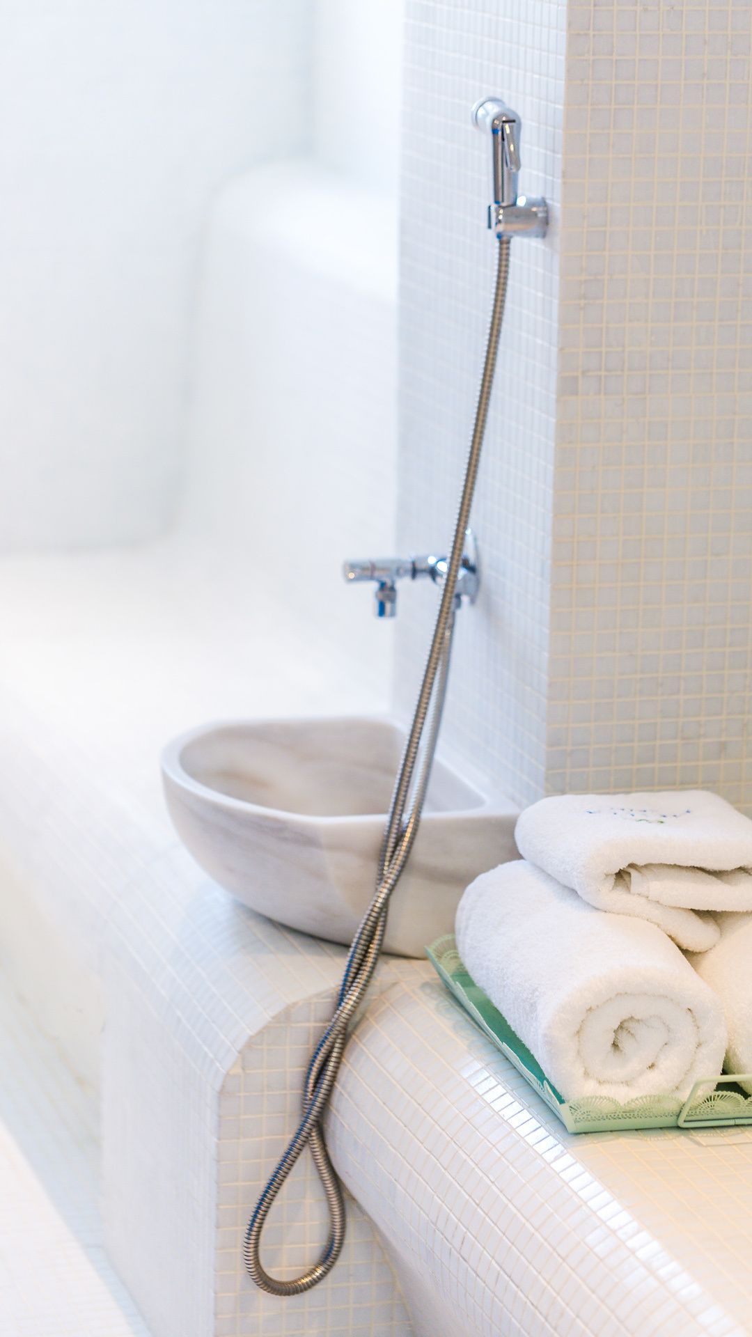 A bathroom with a shower, a bowl, and neatly folded towels.