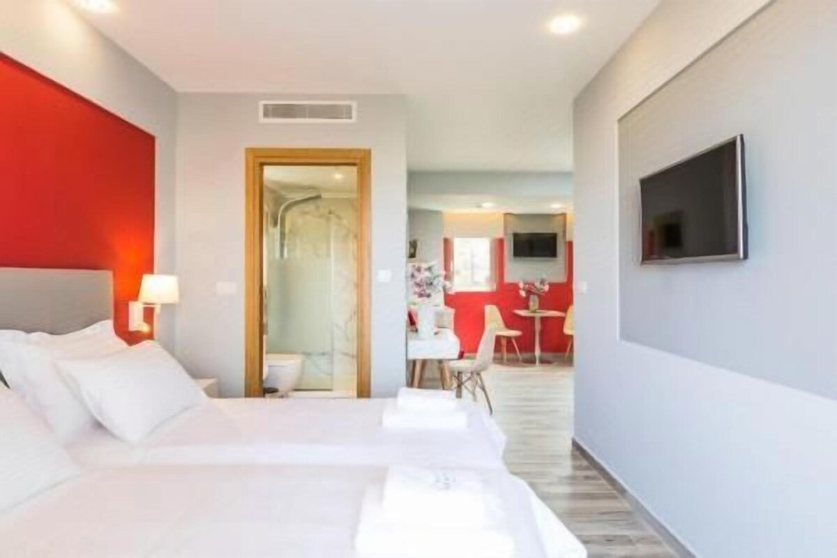 A hotel room with a bed, a TV, and a desk.