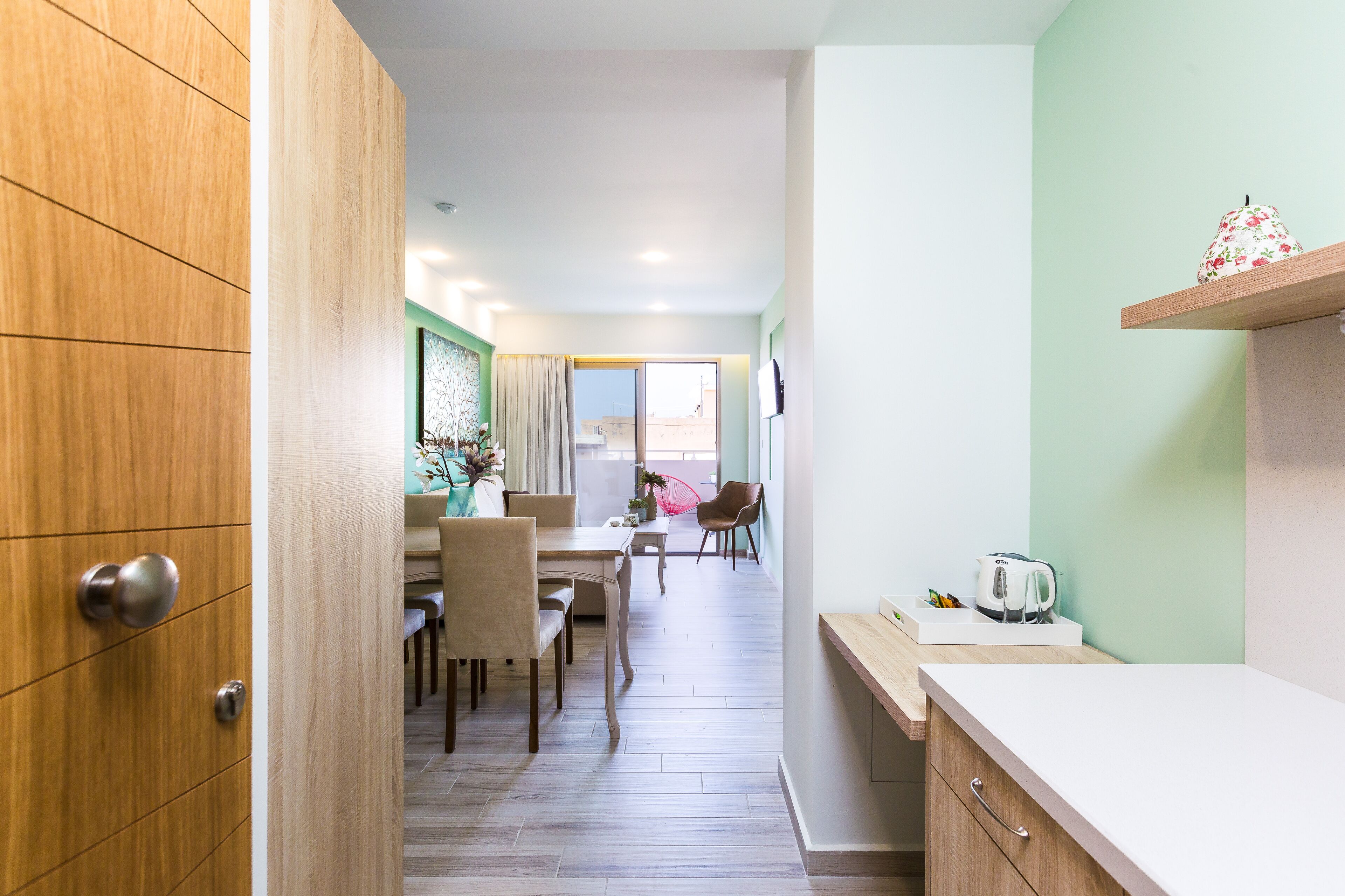 Una cocina moderna con un armario de madera, una encimera blanca y una tetera sobre la encimera.