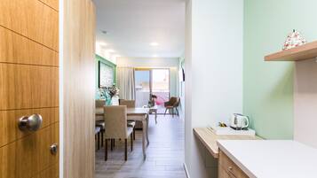 A modern kitchen with a wooden cabinet, a white countertop, and a kettle on the counter.