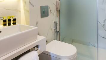 Un baño moderno con tocador de mármol, cabina de ducha de vidrio y retrete.