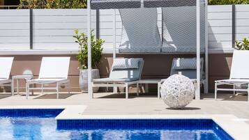 A pool area with lounge chairs, a covered seating area, and a decorative spherical object.