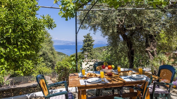 Un área de comedor al aire libre con una mesa para dos, rodeada de vegetación y con vistas panorámicas.