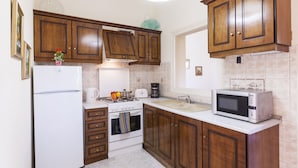 Una cocina con armarios de madera, un refrigerador blanco, una estufa, un microondas y un lavamanos.