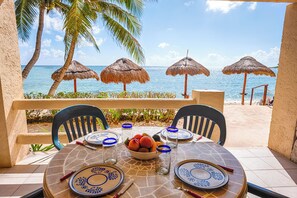 A table set for two with blue and white plates, a bowl of fruit, and a glass of water. - Tropical beachfront condo! AC, swimming pool! (Akumal)
