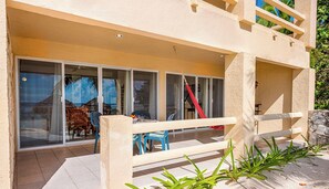 A building with a covered patio area, large sliding glass doors, and a red hammock. - Tropical beachfront condo! AC, swimming pool! (Akumal)