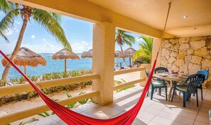A beachside patio with a hammock, chairs, a table, and a view of the ocean. - Tropical beachfront condo! AC, swimming pool! (Akumal)