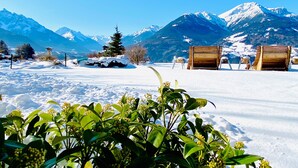 A snowy outdoor area with wooden benches and a mountain backdrop. - Hotel Restaurant Grünwalderhof (Patsch)