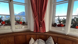 A room with a bay window, wooden paneling, a table set for dining, and decorative pillows. - Hotel Restaurant Grünwalderhof (Patsch)