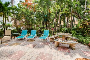 Relax in style with comfortable lounge chairs and a mosaic table amidst lush greenery and scenic views.