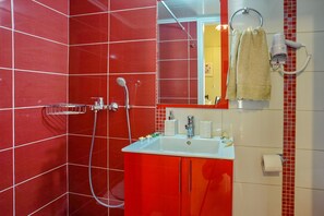 A bathroom with red tiled walls, a white sink, and a handheld showerhead. - Loggos Panoramic Views Electra By Konnect (Paxos)