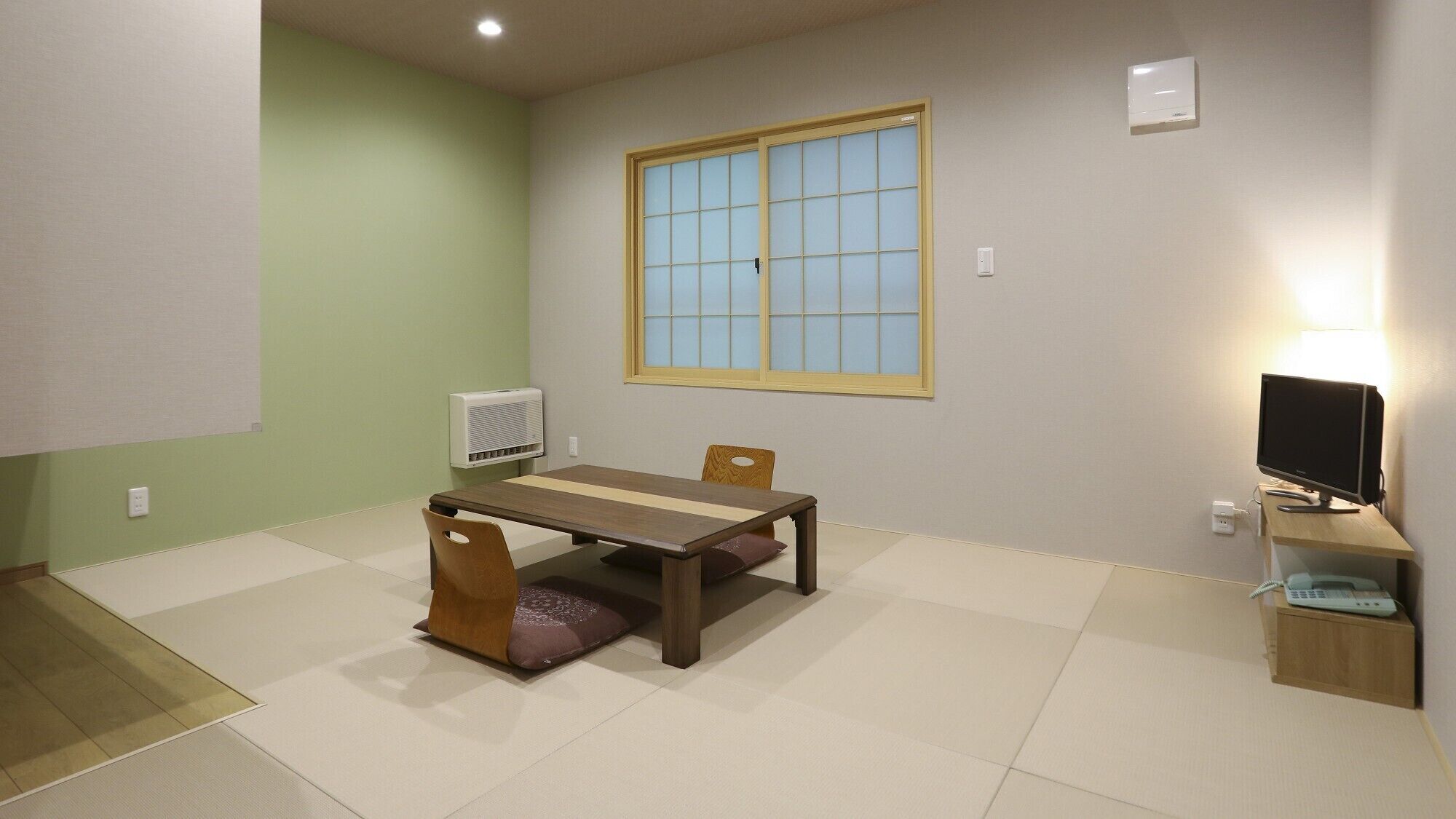 A room with a table, chairs, a TV, and a window.