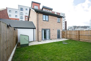 A two-story residential building with a brick facade, a small attached garage, and a fenced backyard. - KVM - Quayside House (Peterborough)