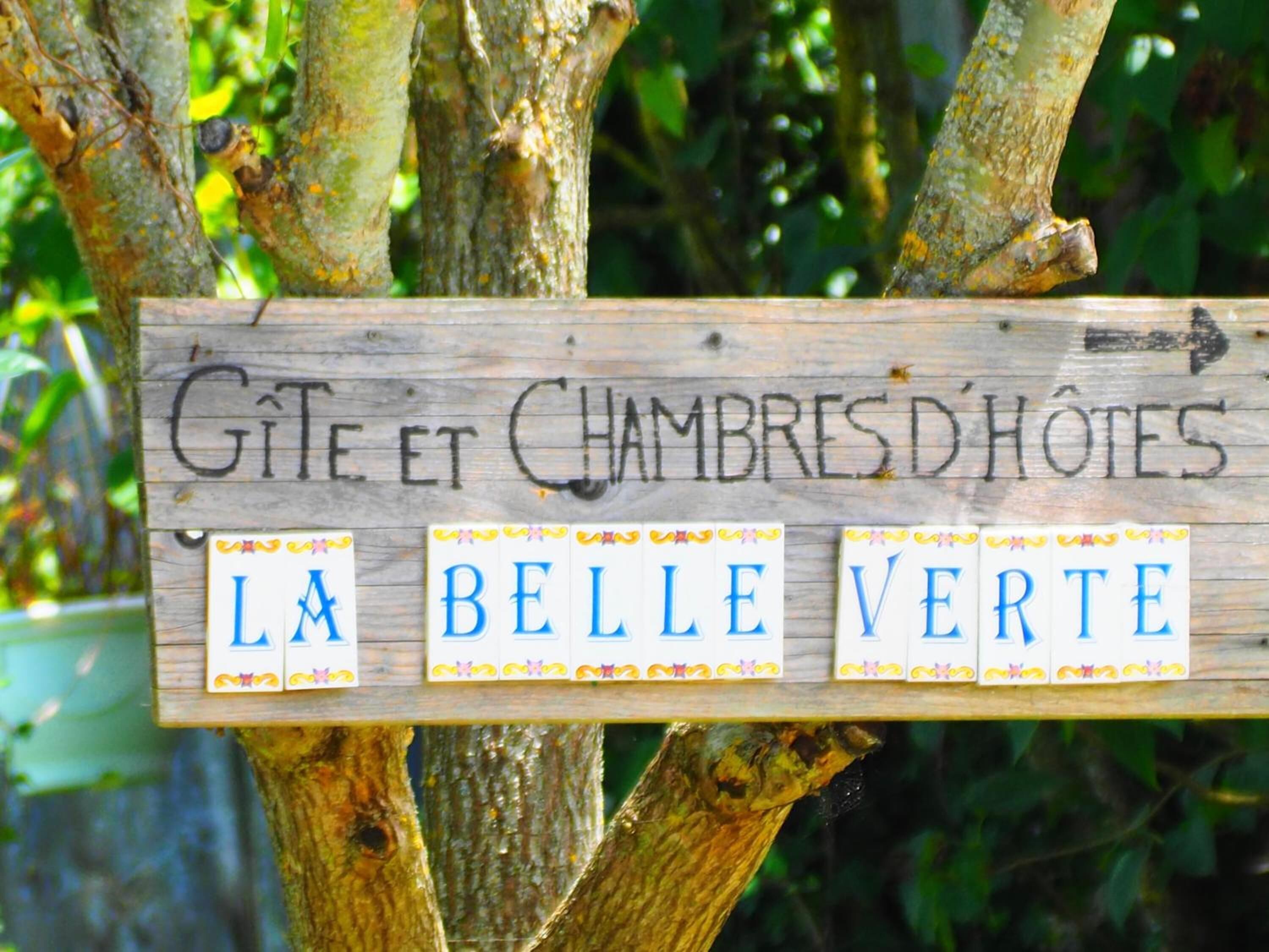 Señal de madera que indica un alojamiento con la inscripción 'Gîte et Chambres D'Hotes' y 'La Belle Verte'.