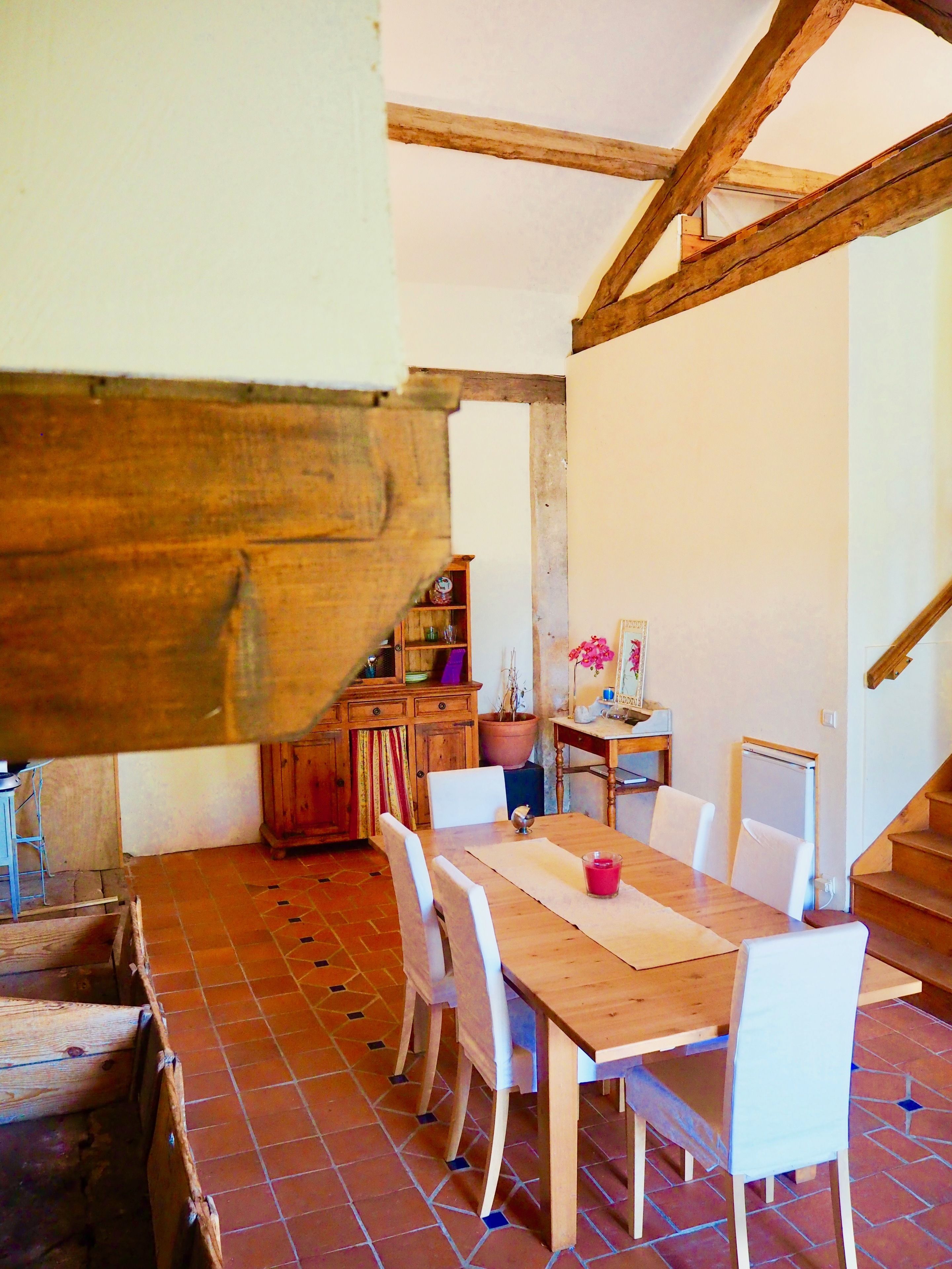 Un coin repas rustique avec une table et des chaises en bois, un sol carrelé et un escalier en bois.