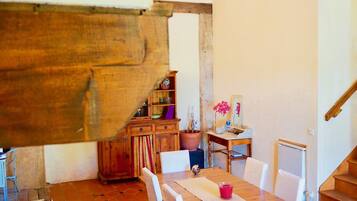 Un coin repas rustique avec une table et des chaises en bois, un sol carrelé et un escalier en bois.