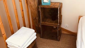 Une pièce rustique avec un banc en bois, une petite table en bois sur laquelle est posée une lanterne, et une serviette blanche sur une commode en bois.