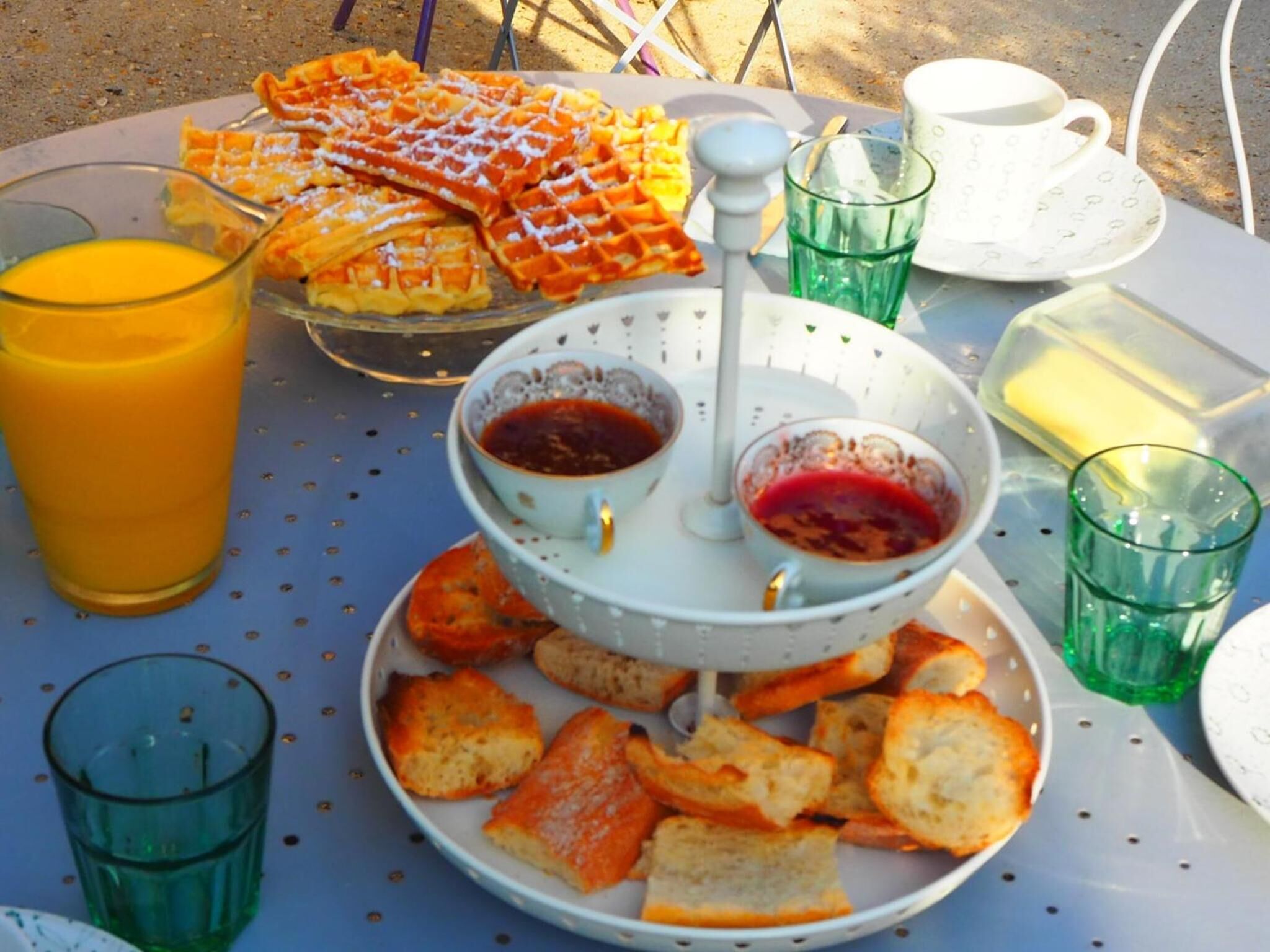 Una mesa de desayuno con waffles, tostadas y un bol de fruta.