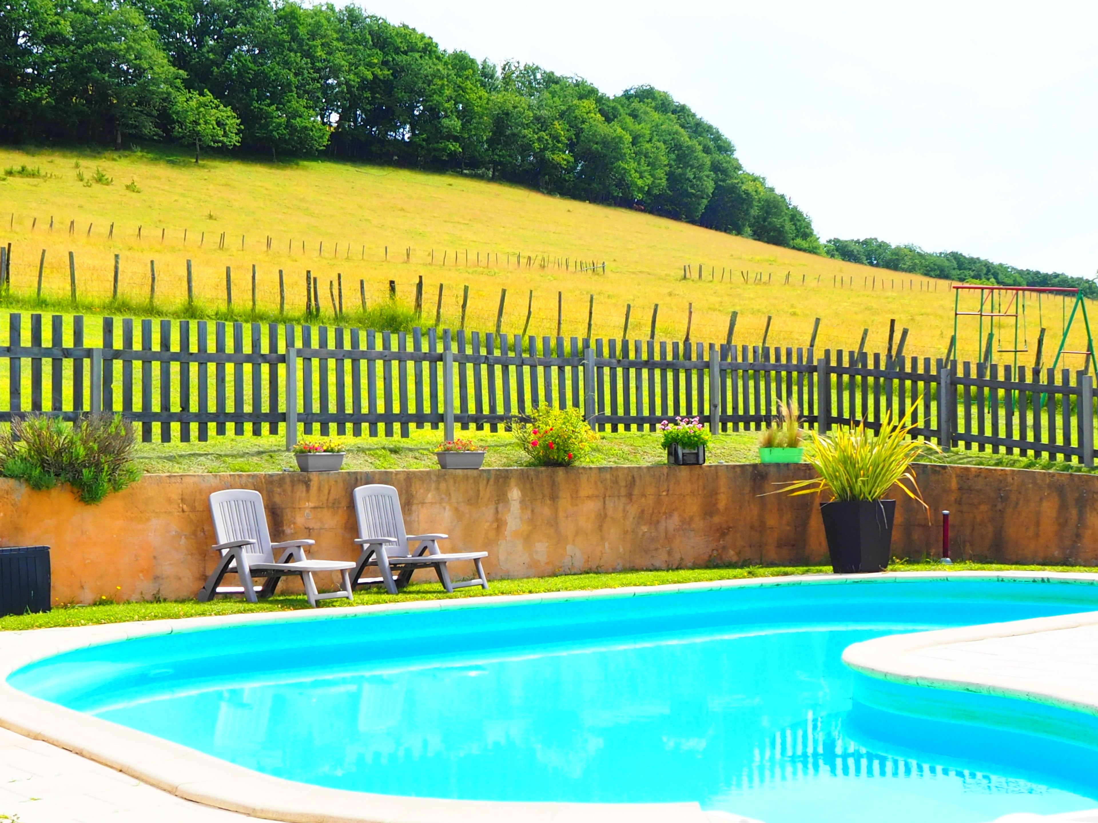 Une piscine avec deux chaises longues et une clôture en bois en arrière-plan.