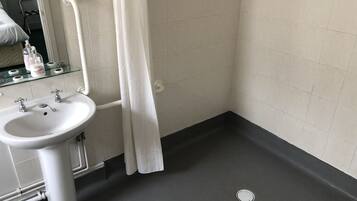 A bathroom with a white sink, a glass shelf with toiletries, and a shower curtain.